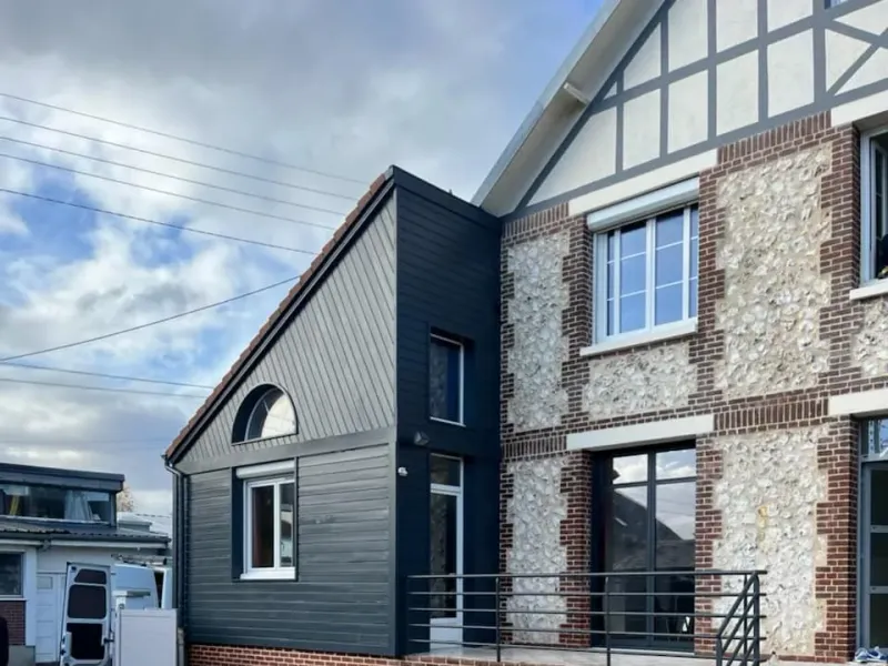 Pignon à colombages et façade en silex rénovés sur une maison normande
