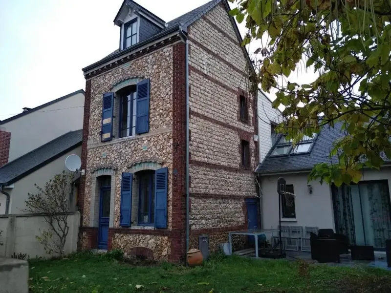 Maison en pierre de silex et brique avec volets bleus et lucarne en toiture ardoise
